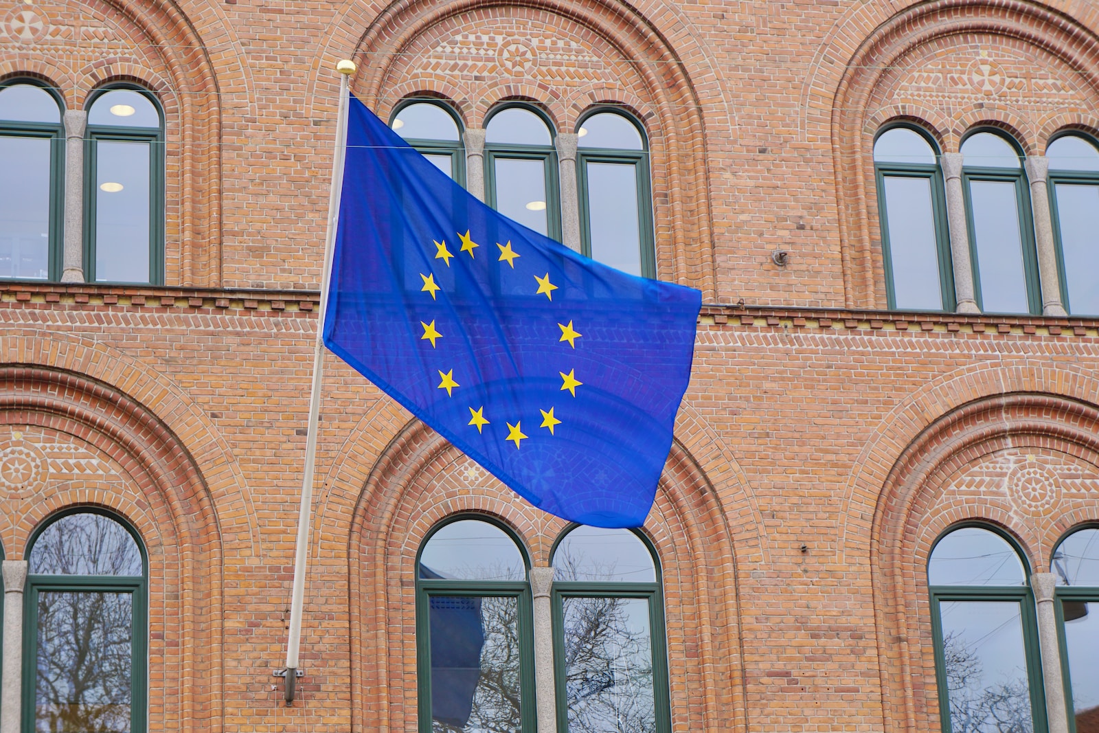 a european flag flying in front of a brick building