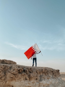 Hombre de pie sobre la roca con una bandera de Bahrein