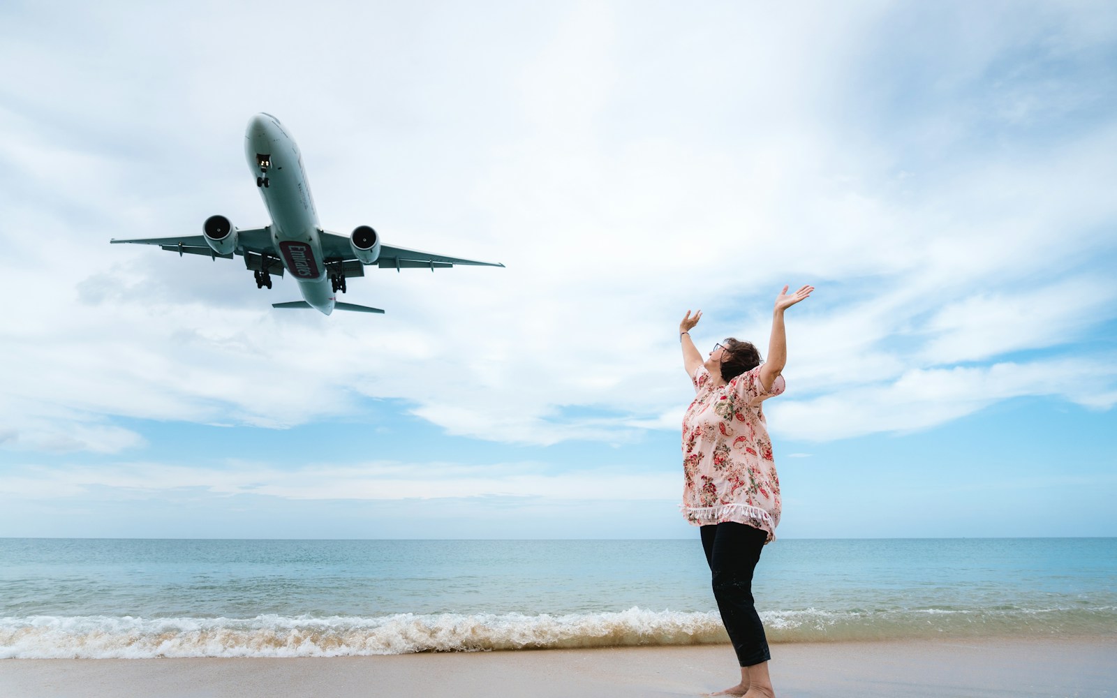 a woman standing on a beach next to an airplane